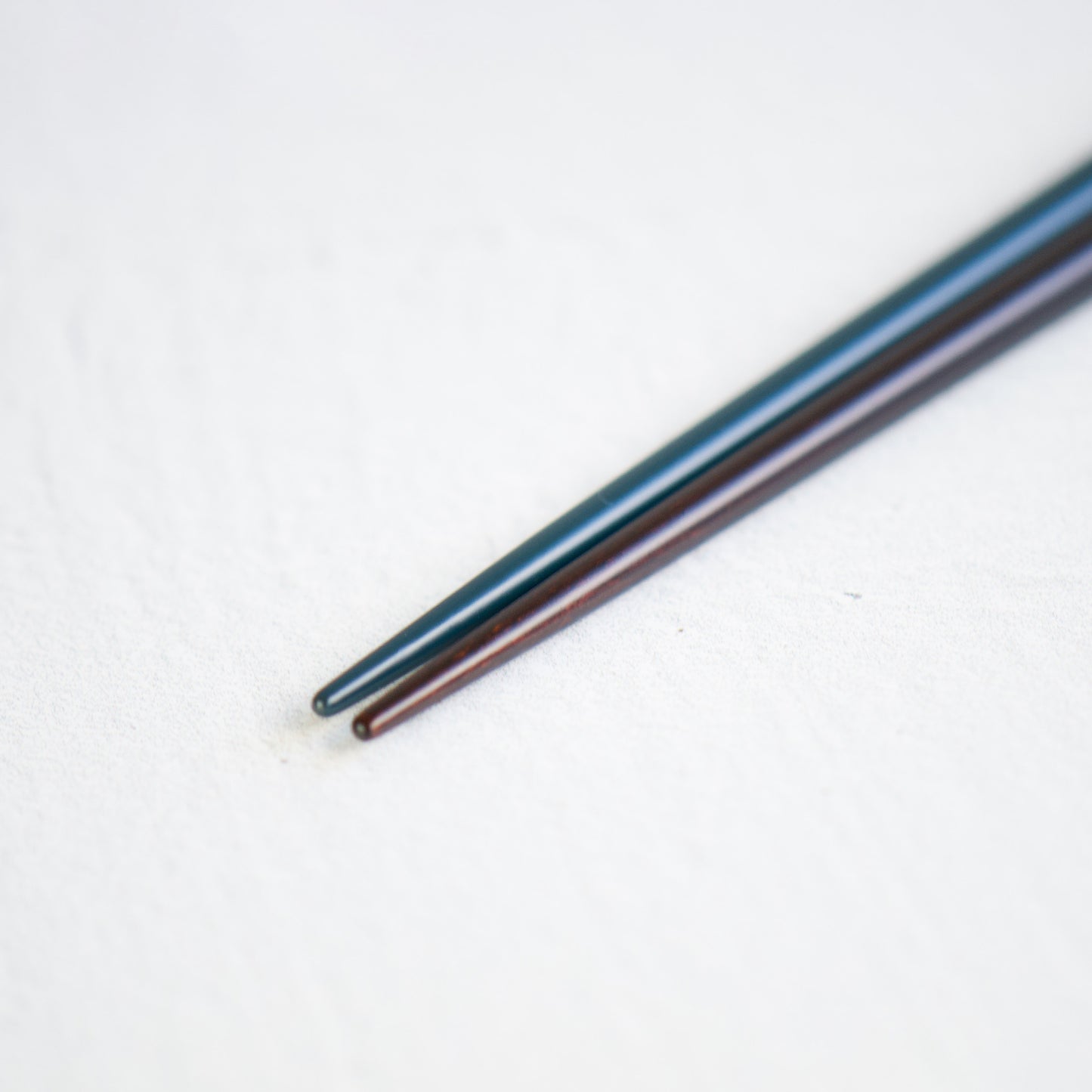 A close-up view of the pointed but well-rounded lacquered heads of the navy and black chopsticks, perfect for precise food handling.