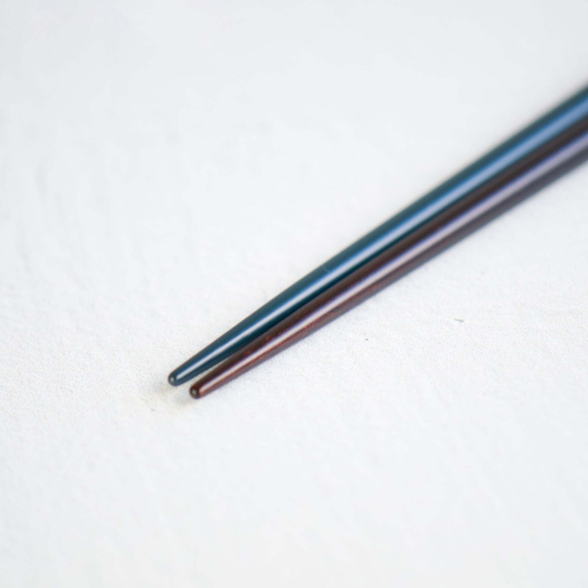 A close-up view of the pointed but well-rounded lacquered heads of the navy and black chopsticks, perfect for precise food handling.