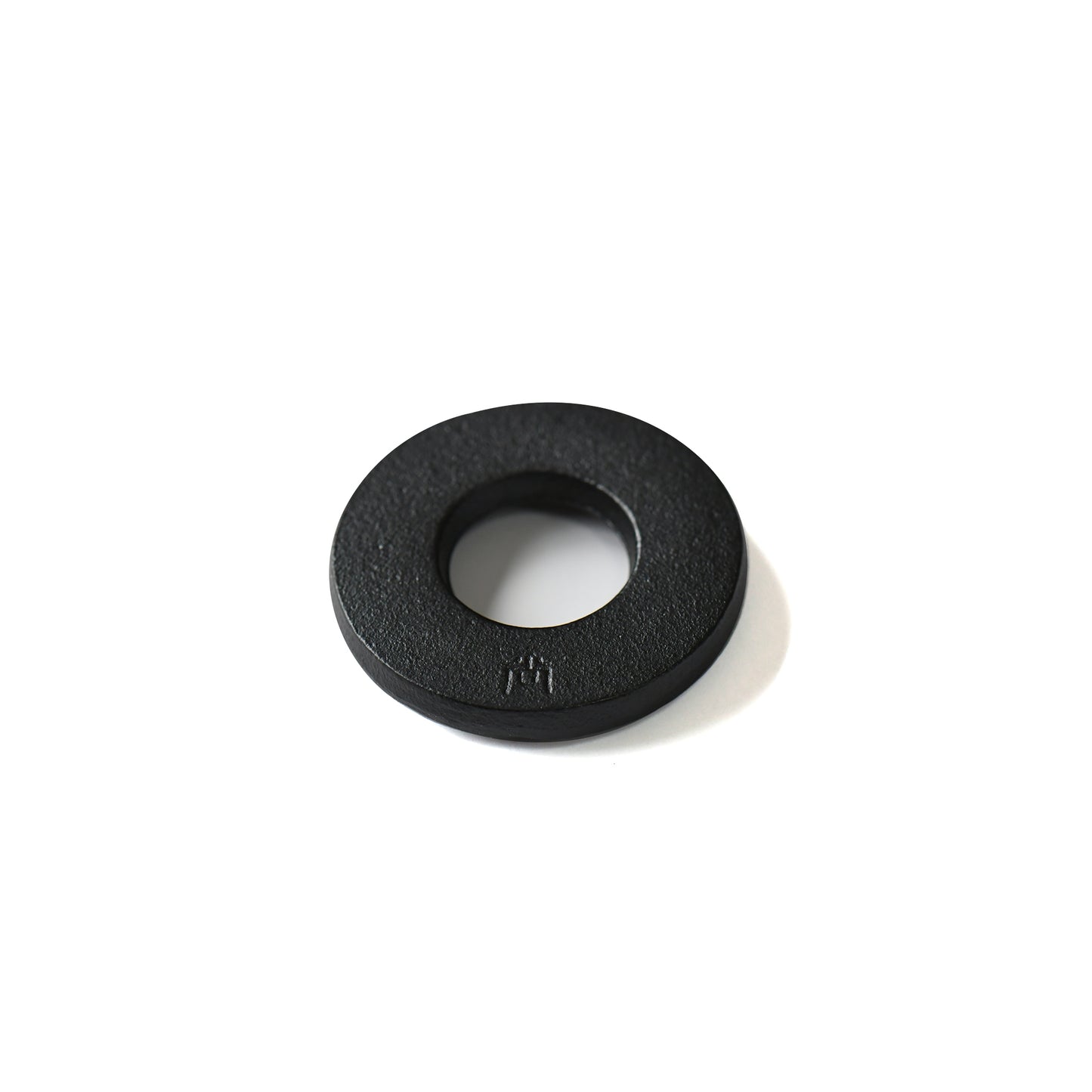 Back view of Kokuyo iron chopstick rest showing textured black surface and rounded shape with artisan's signiture logo.