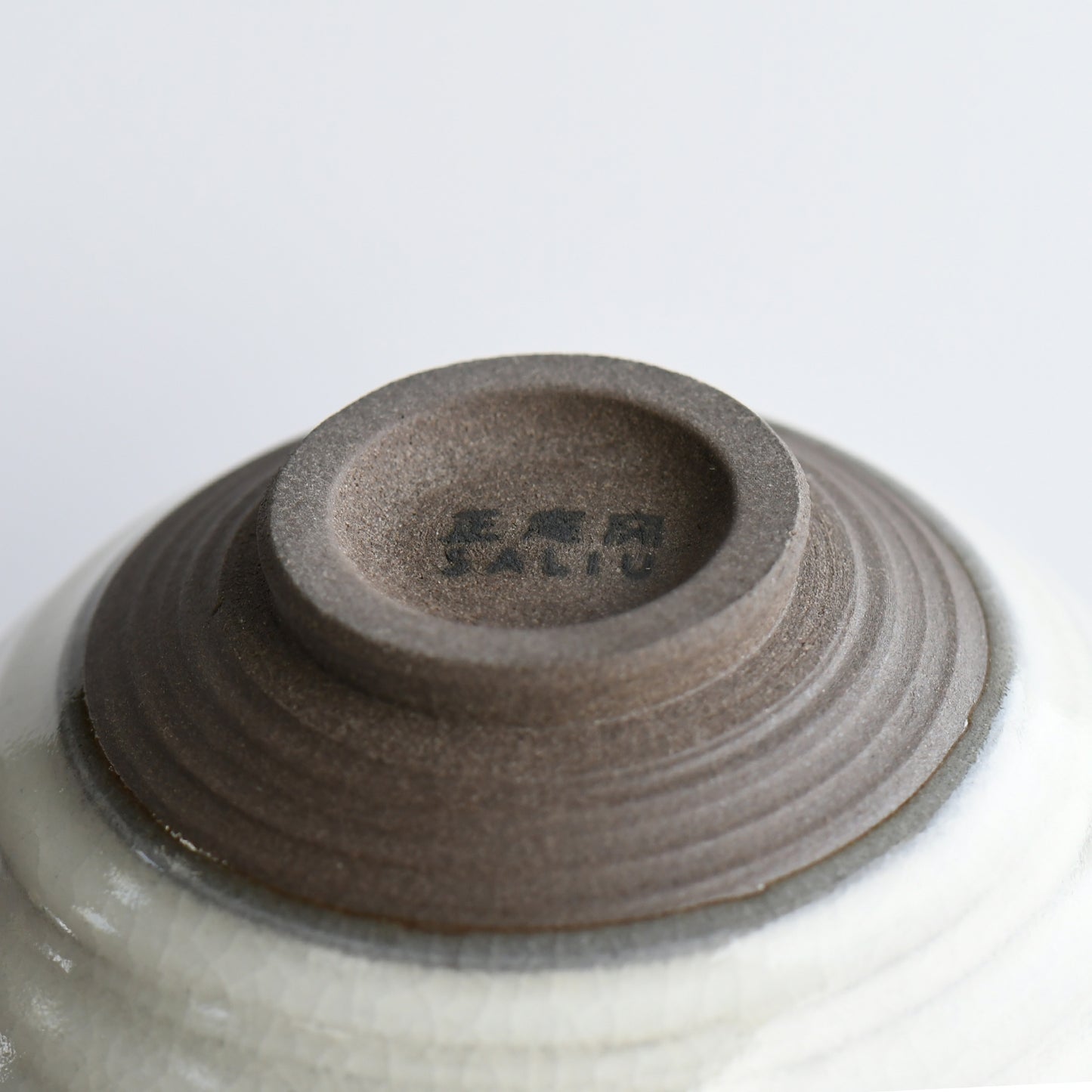 Bottom view of Hakuei matcha bowl showing natural clay foot and Shoan Kiln mark