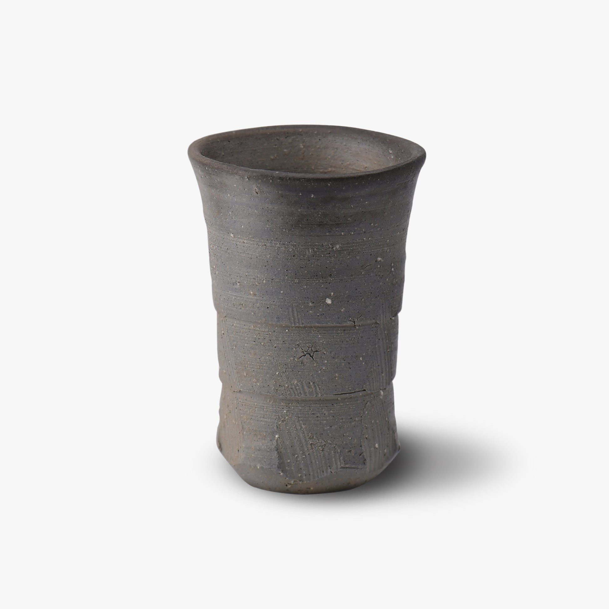 A dark gray ceramic tumbler with a textured surface, likely handcrafted.