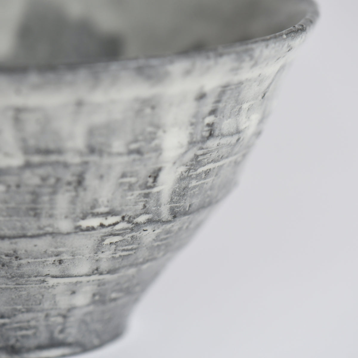 Close-up of the charcoal-gray textured surface and layered white glaze of the handmade Sumine Rice Bowl.