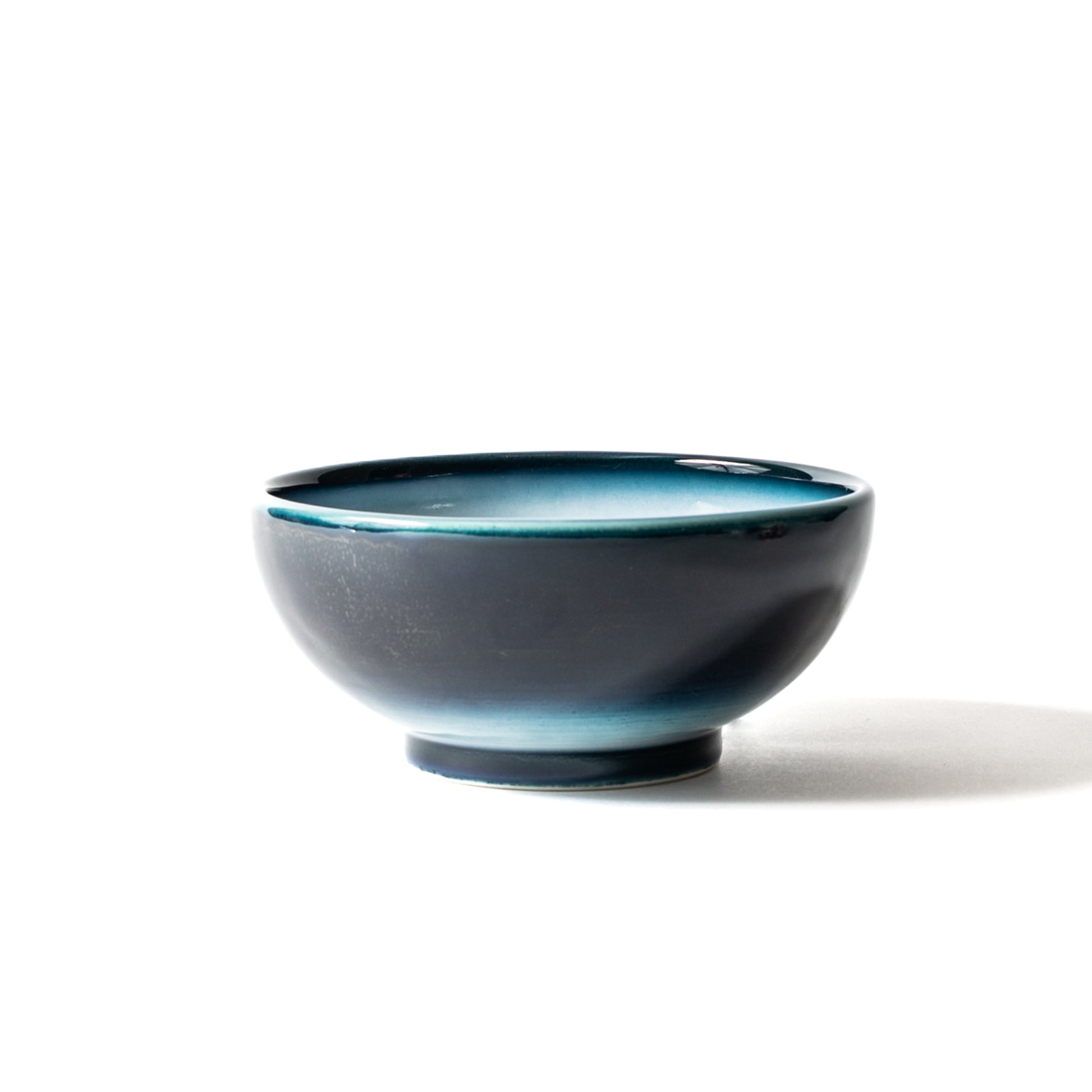 Side view of Shima White donburi bowl—matte exterior navy gradient with luminous white interior rimmed in teal.